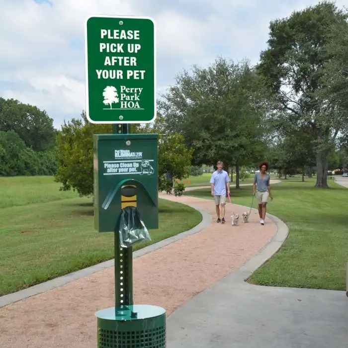 Professional pet waste station installed at a community park with dog walkers using the path